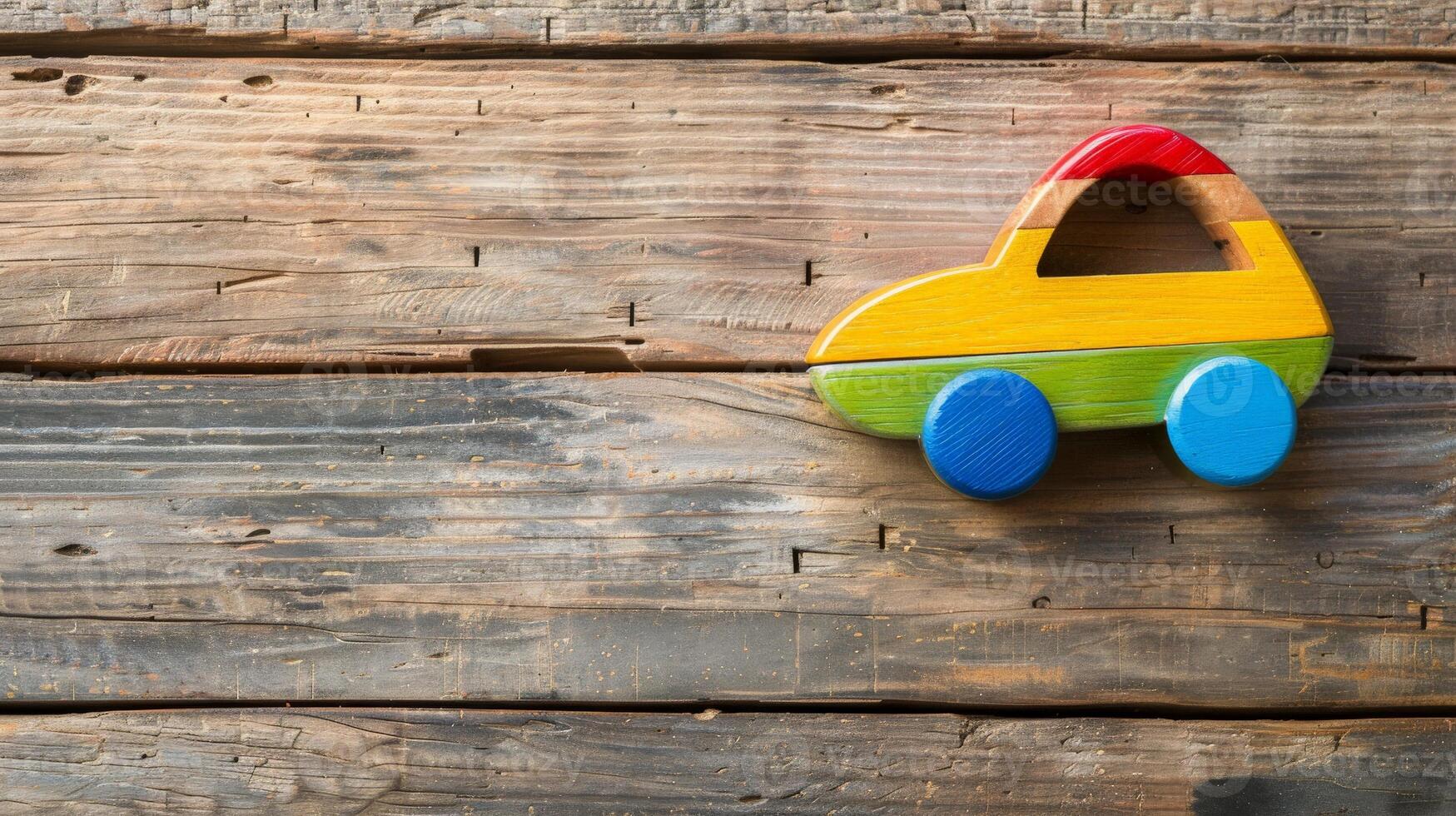 A colorful wooden toy car sits on a rustic weathered wooden surface photo