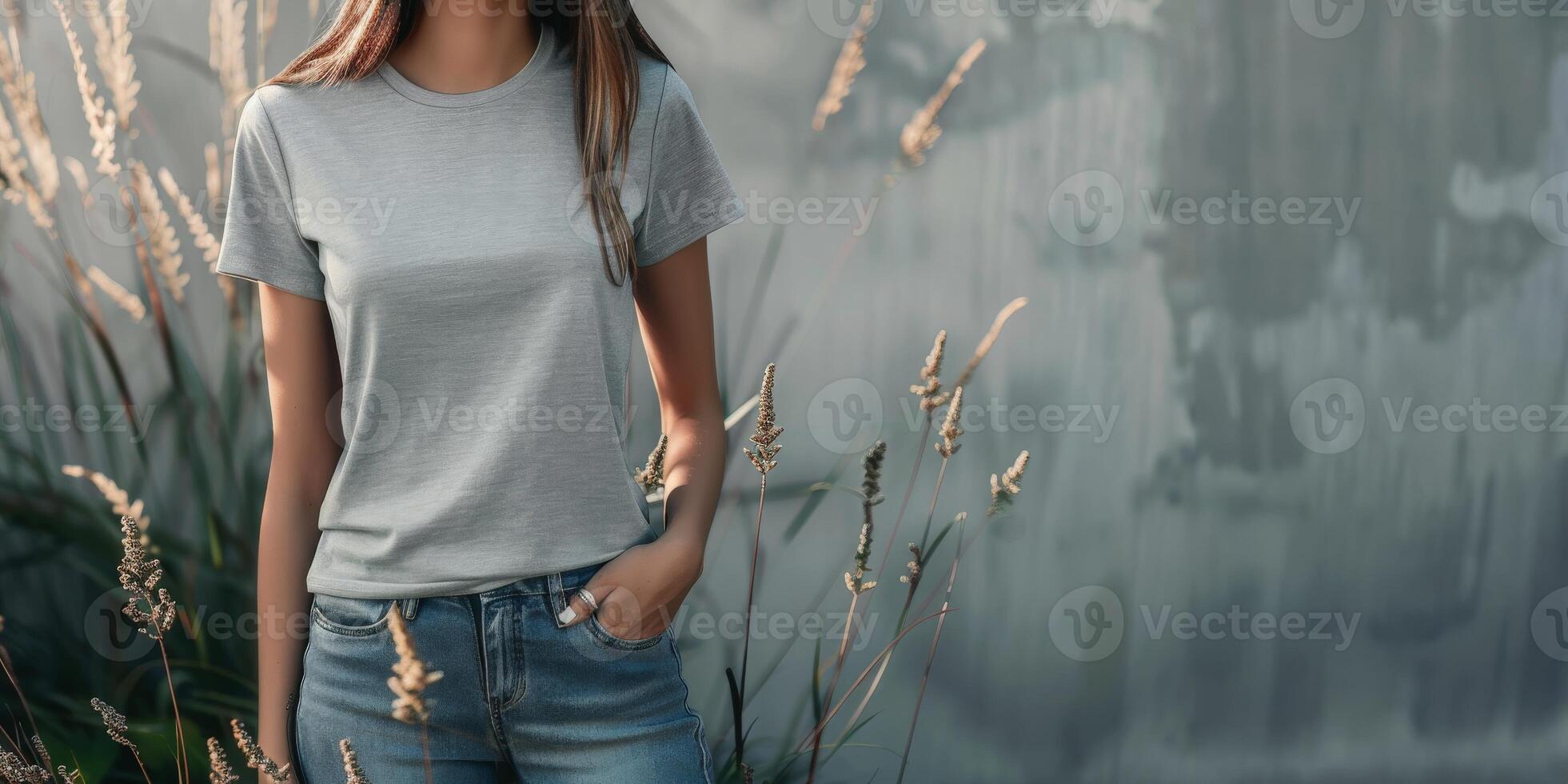 A woman wearing a blank t-shirt stands near a wall with plants photo