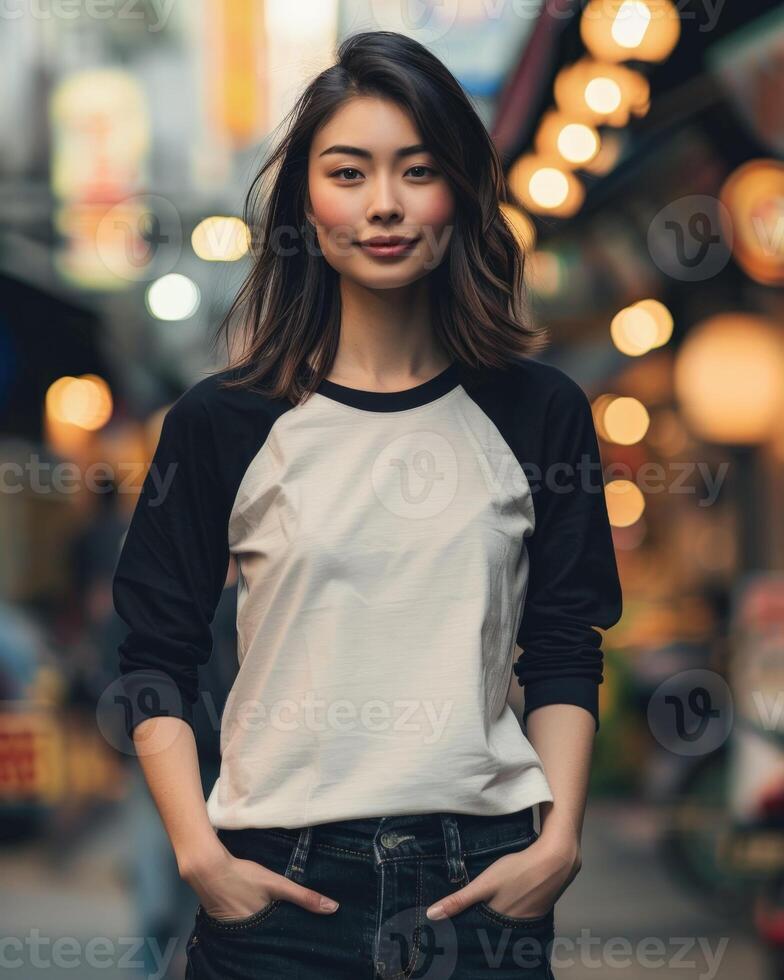 A woman wearing a white raglan shirt poses against a backdrop of urban city lights photo