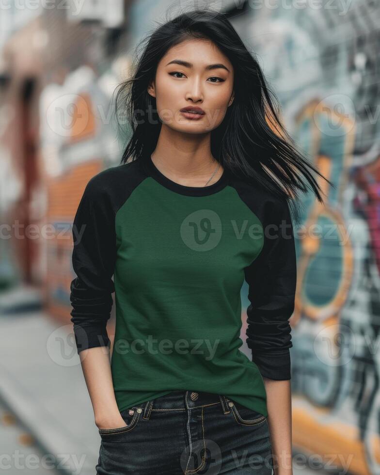 A woman wearing a green and black raglan t-shirt stands in an urban setting photo