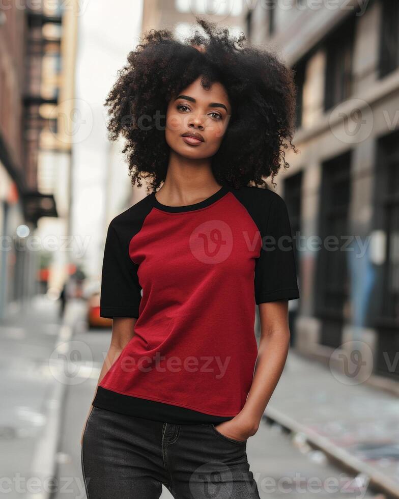 A young woman stands in a city setting wearing a red raglan shirt photo