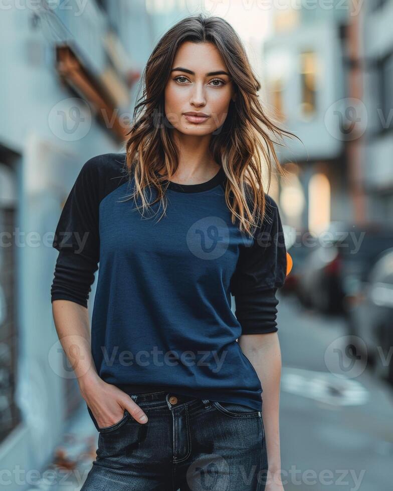 A woman wearing a blue and black raglan shirt stands confidently on a city street photo