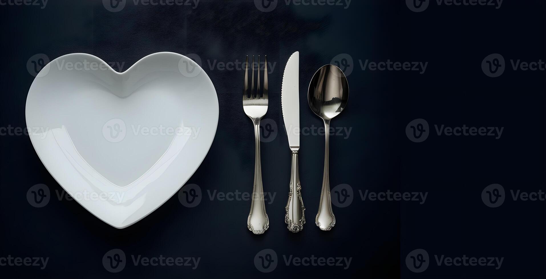 An empty white heart shape plate along with cutlery are presented on dark background photo