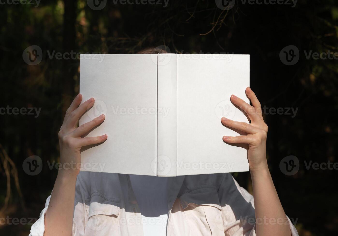 . Hands holding open book, cover mockup, hiding face with literature, sunny summer day. photo