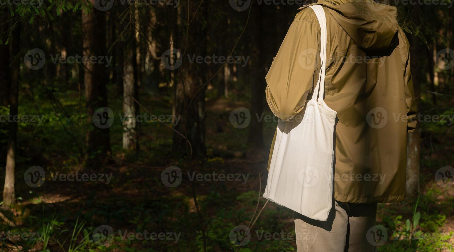 . Canvas tote bag on male shoulder, nature forest background. Banner photo