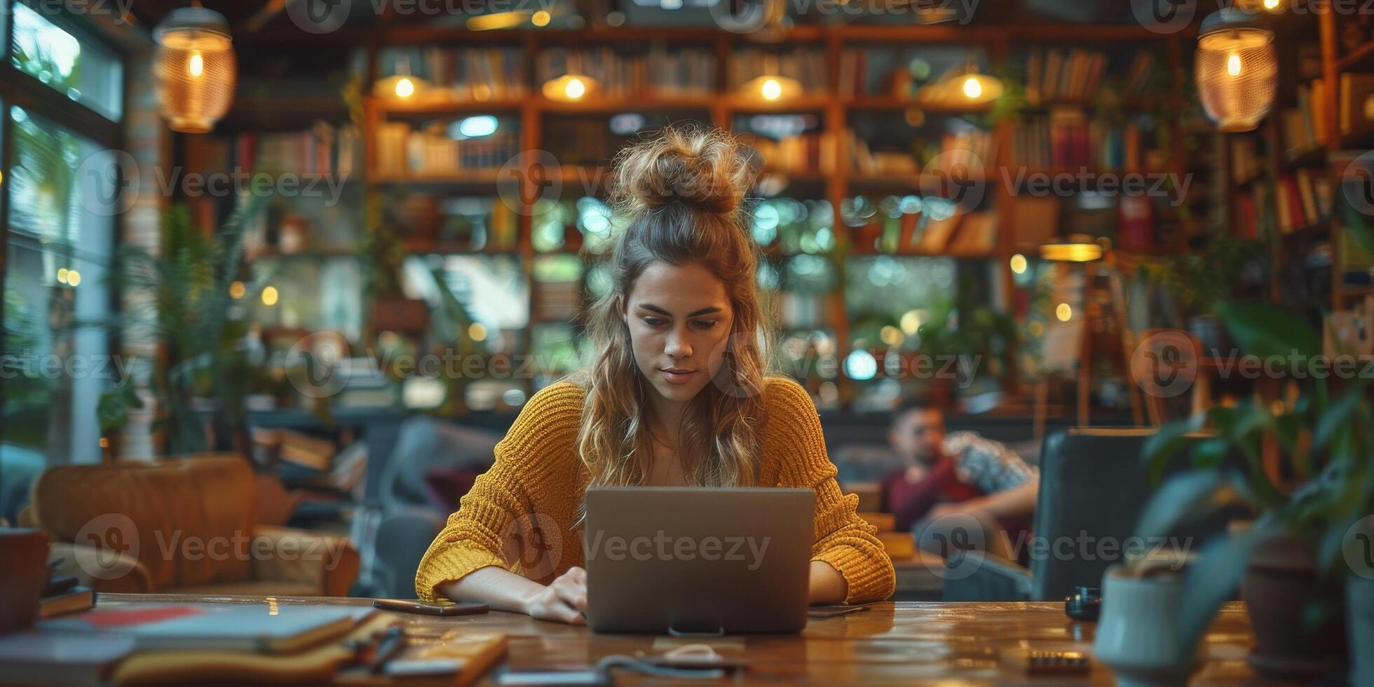 A woman is seated at a table, happily using a laptop computer photo