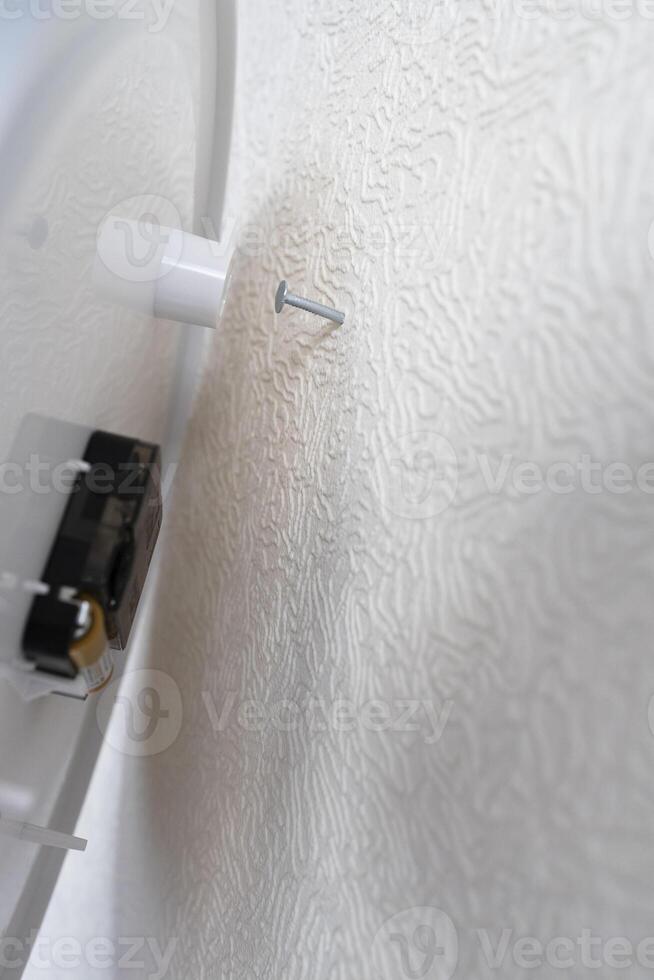 wall clock is placed on nail driven into wall photo