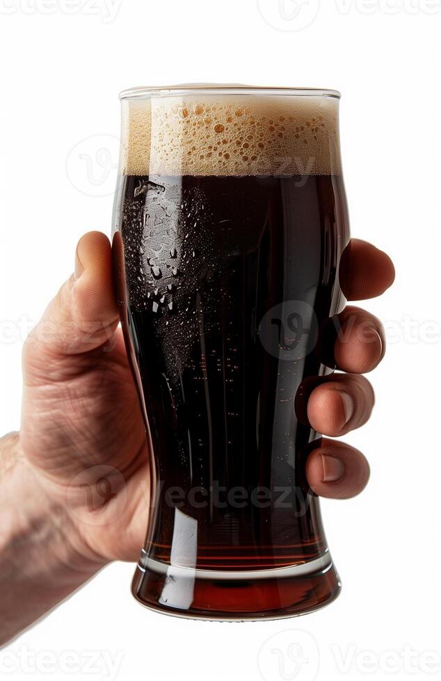 Close up of a man's hand holding a glass with dark beer isolated on a white background photo