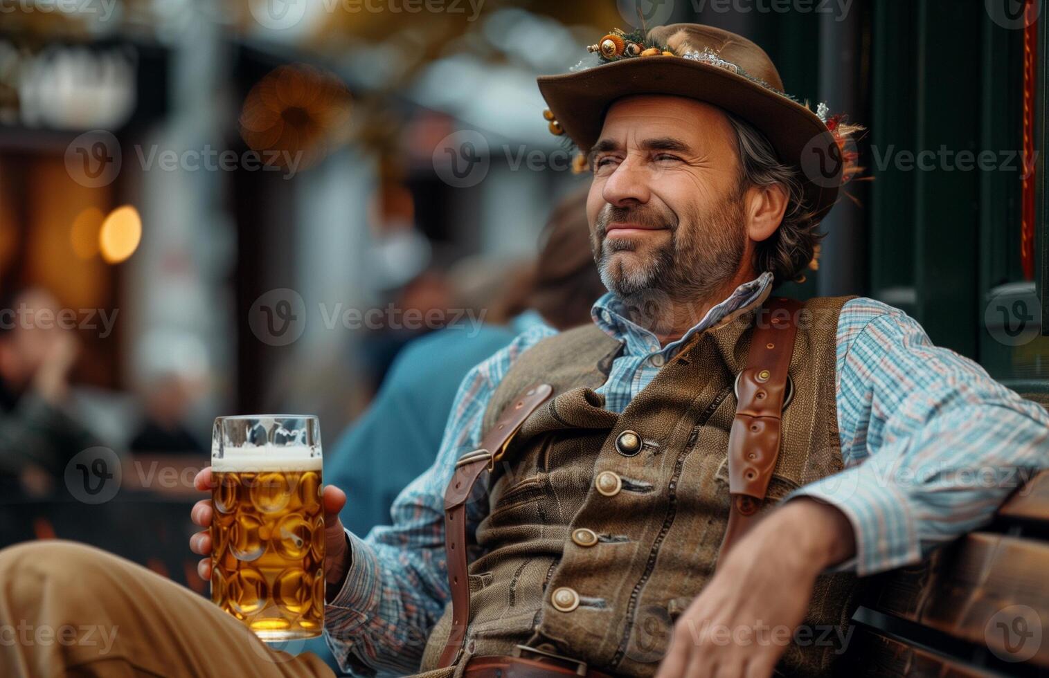 Handsome man in traditional Bavarian attire drinking beer from a large glass while sitting on a bench photo
