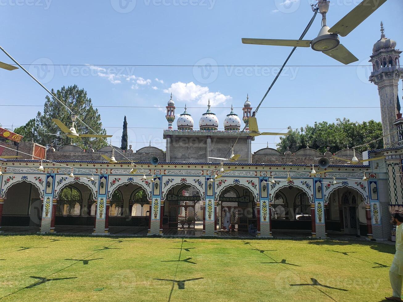 A beautiful Mosque with a garden and fans hanging with iron rob and sky photo