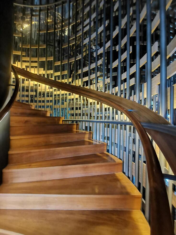 Modern spiral stairs. Curved staircase with wooden treads leading upwards in modern building interior. photo
