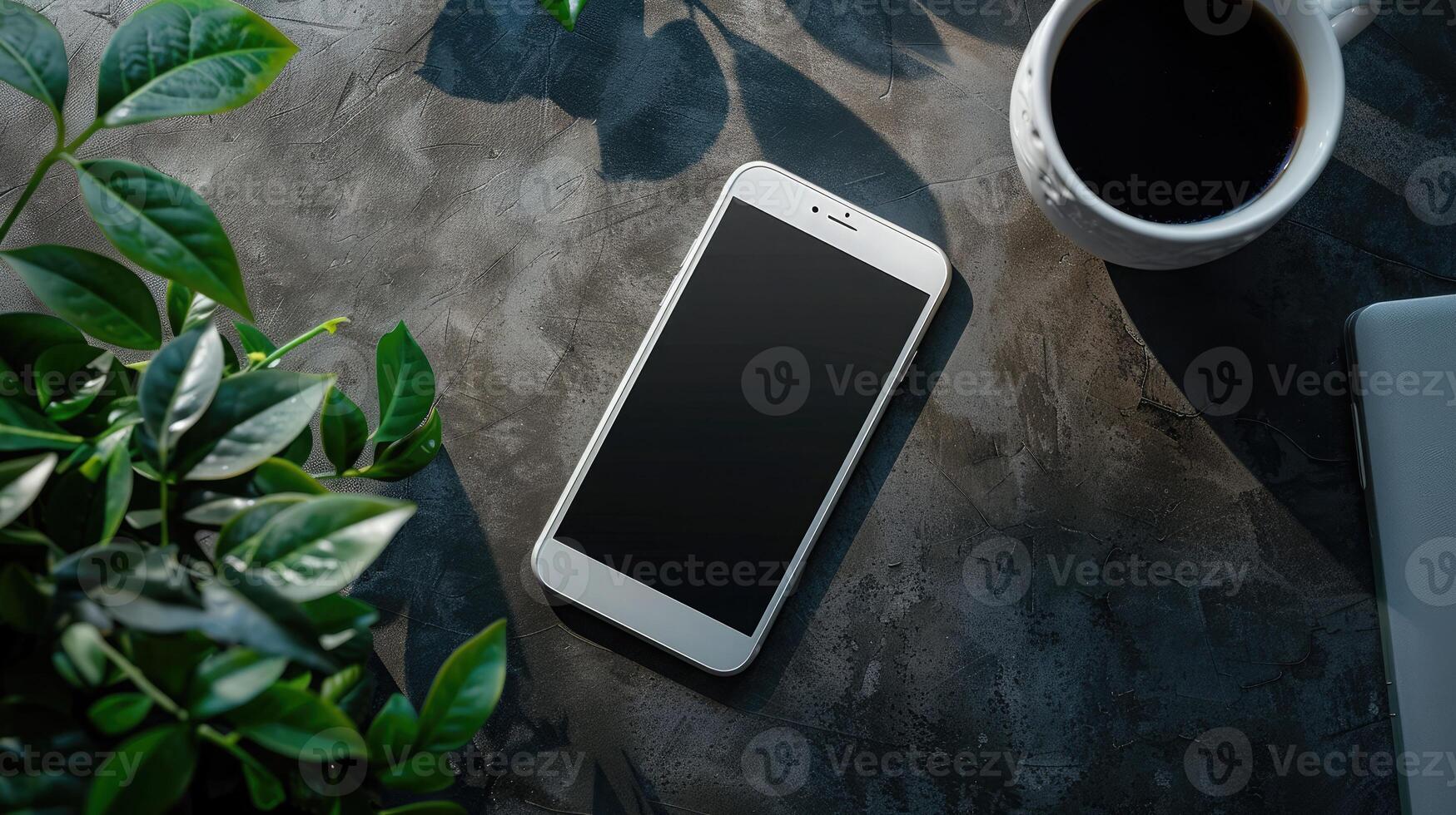 Top view of modern workspace with laptop, smartphone and plant on dark table photo
