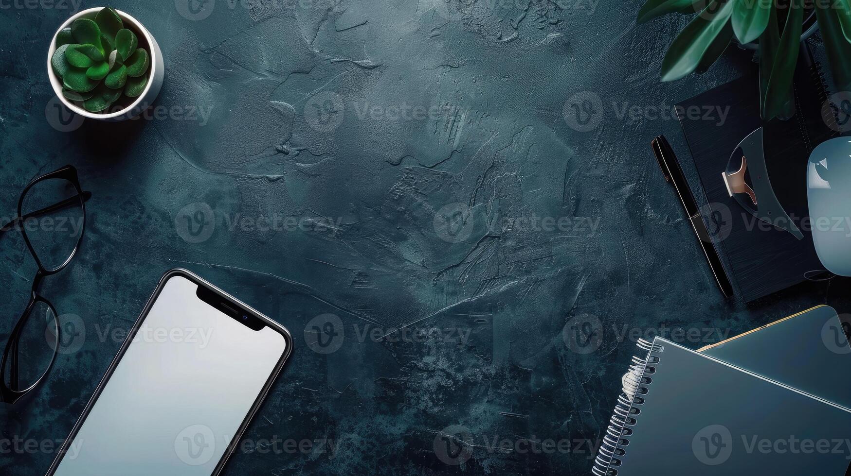 Top view of modern workspace with laptop, smartphone and plant on dark table photo