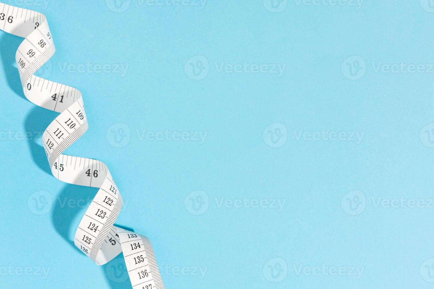 Measuring tape on blue background with copy space. Weight or length concept photo