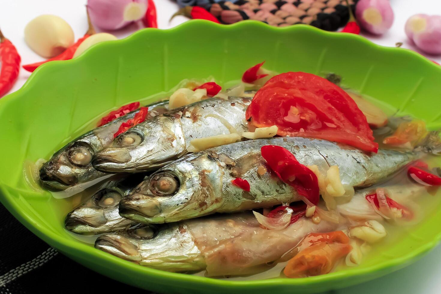 Boiled fish contain fish, sauce, chilies, tomatoes, spices, onions served in a bowl isolated on white background photo