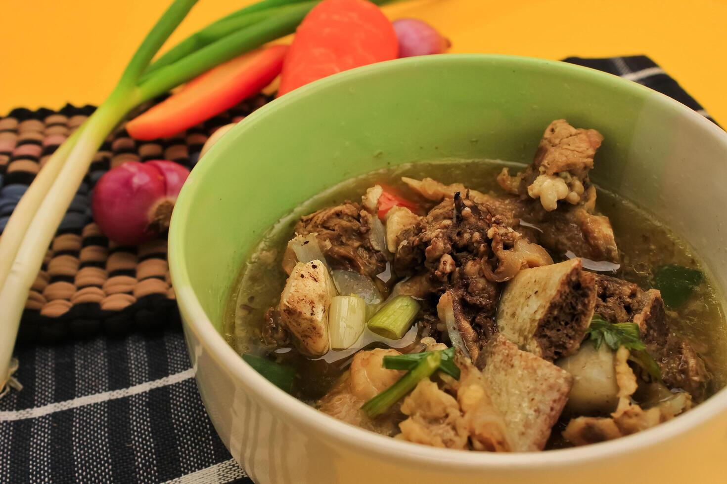 Rib soup is served in a bowl containing rib meat, sauce, carrots, celery, chilies, spring onions. rib soup on isolated background. Rib soup is a favorite food of Asian people photo