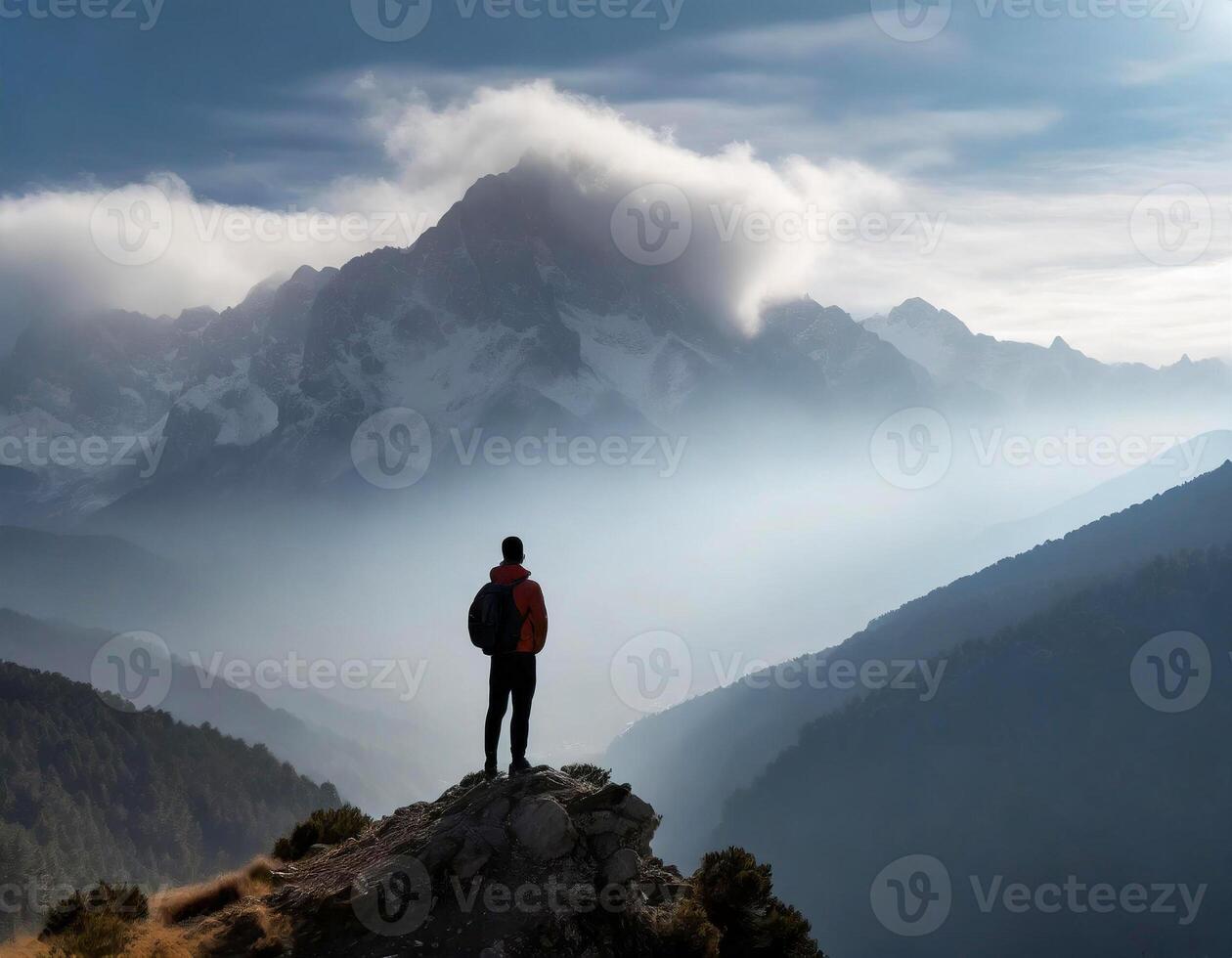 Photo of a man standing on a smoky mountain peak at the summit. Hiker on top of mountain.