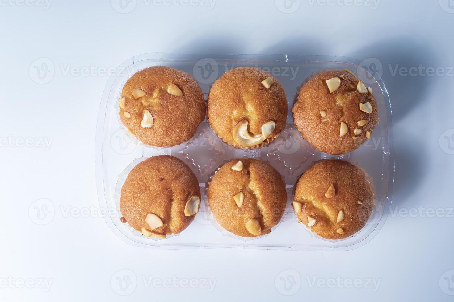 Freshly baked almond muffins in a transparent plastic tray on a white background. photo