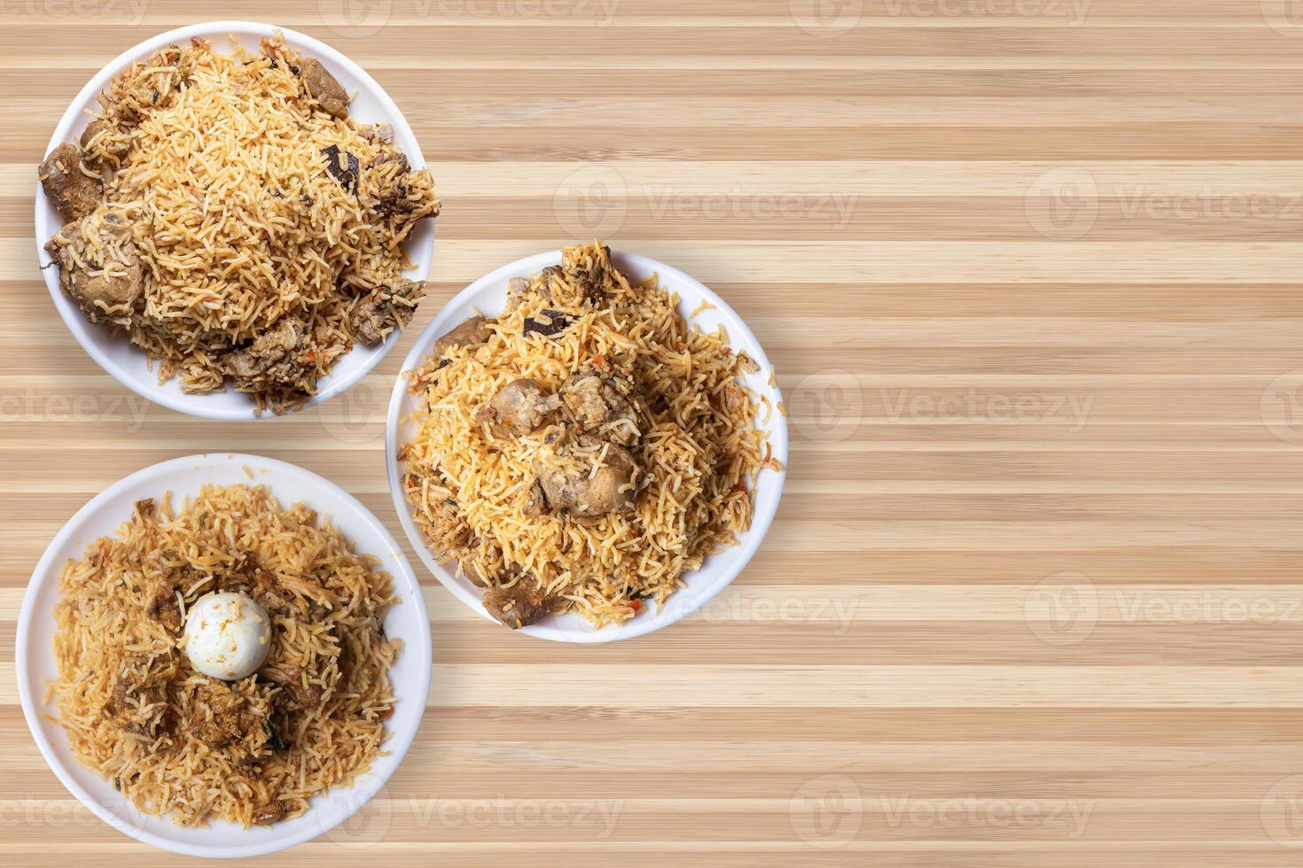 Indian famous biryani dishes on white plate. Chicken biryani, mutton biryani, egg biryani on wooden table. photo