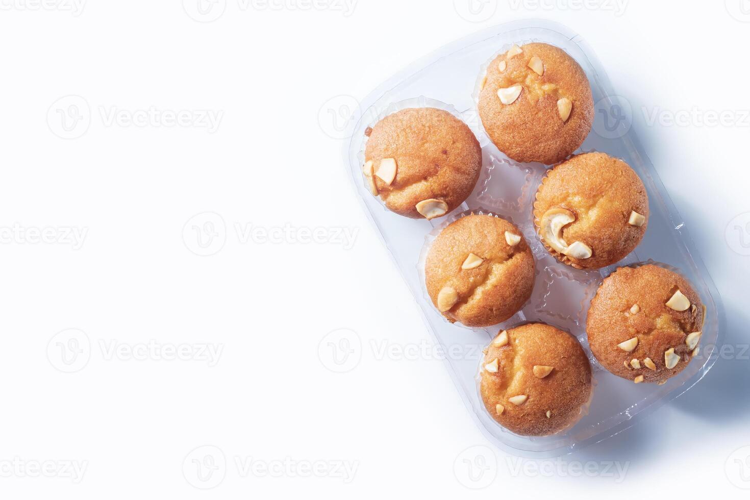 Freshly baked almond muffins in a transparent plastic tray on a white background. photo