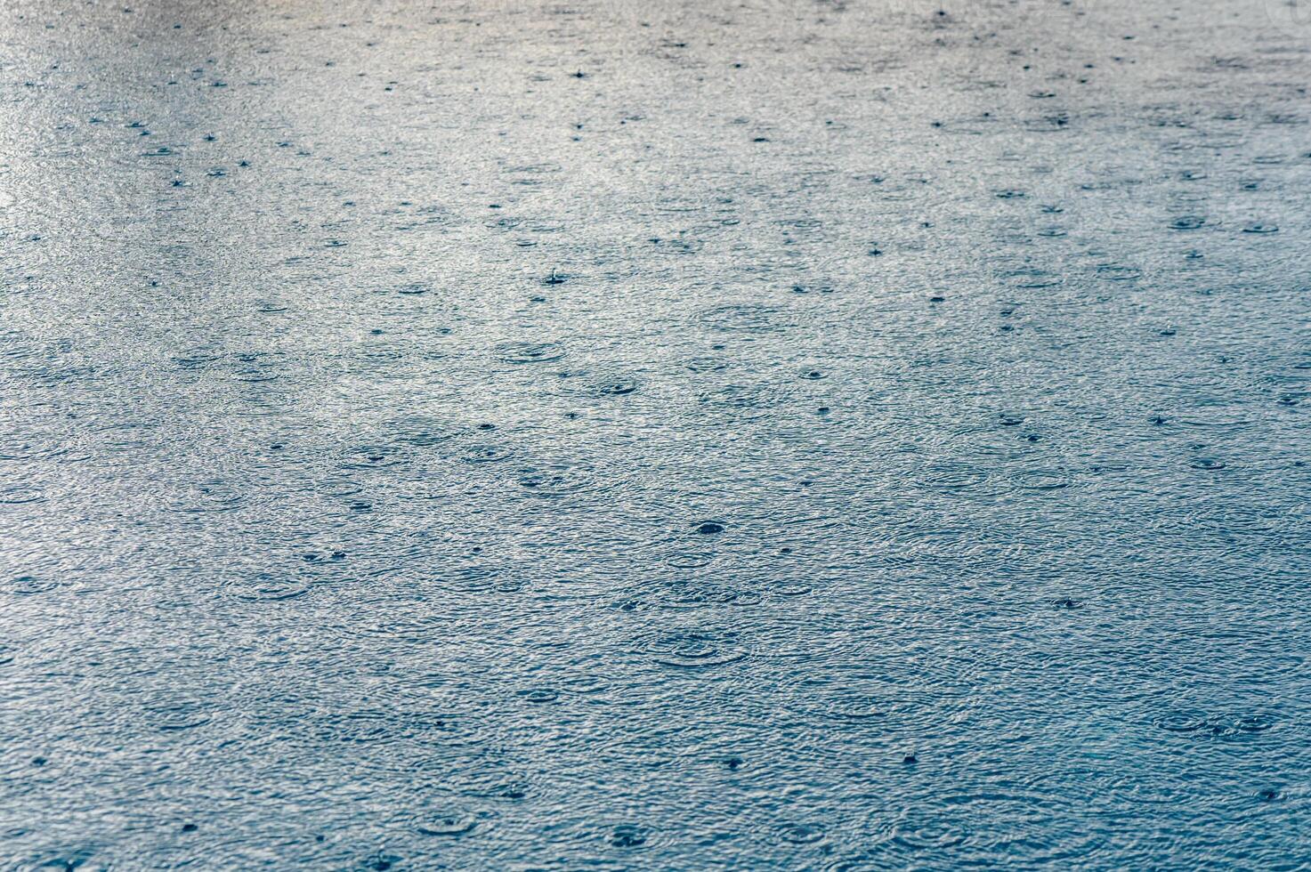 Defocus blurred transparent blue colored clear calm water surface texture with splashes and bubbles. photo