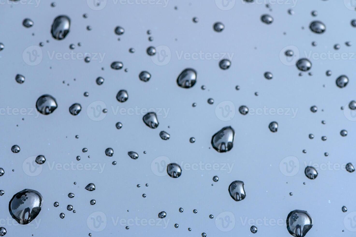 Glass with rain drops against gray background. 3 photo