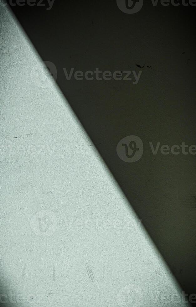 , diagonally divided gray wall casting a shadow as a background photo