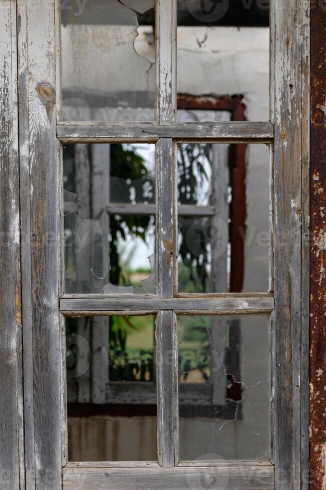 Window with broken glass in old building Wooden window frame with partially broken glass in old abandoned brick building photo
