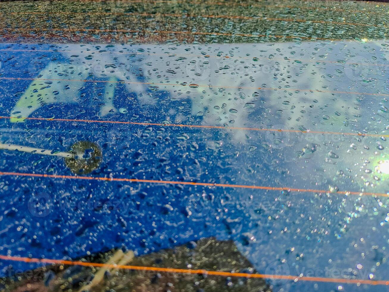 Raindrops on the clean car glass image with silver color car on the background photo