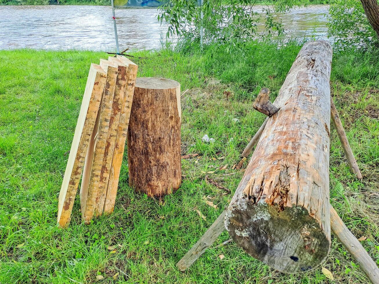 Planks and logs lie on the grass by the river, seasoning for building a raft. photo