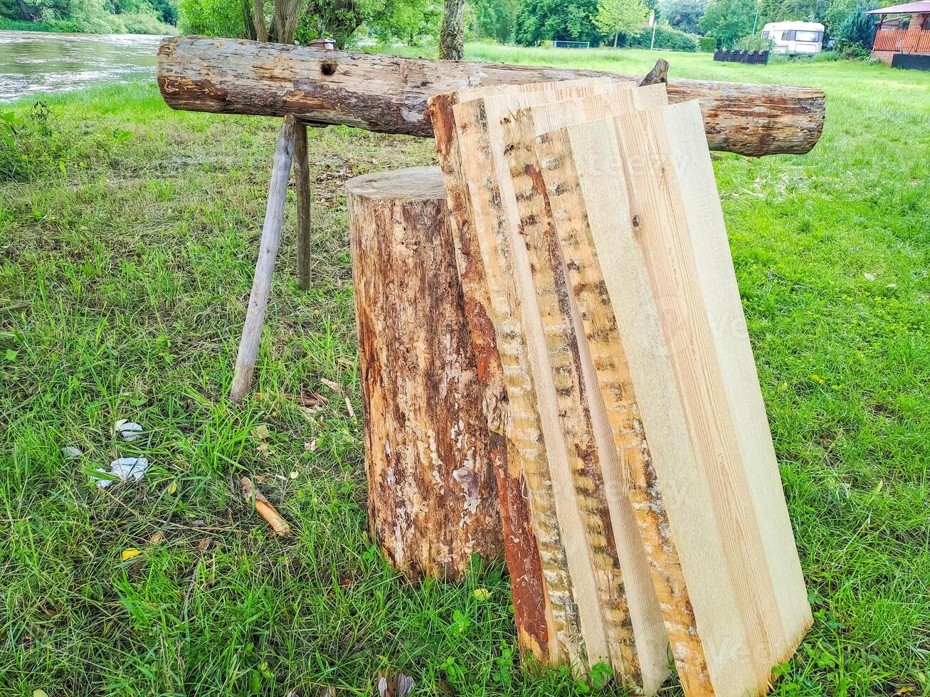 Planks and logs lie on the grass by the river, seasoning for building a raft. photo