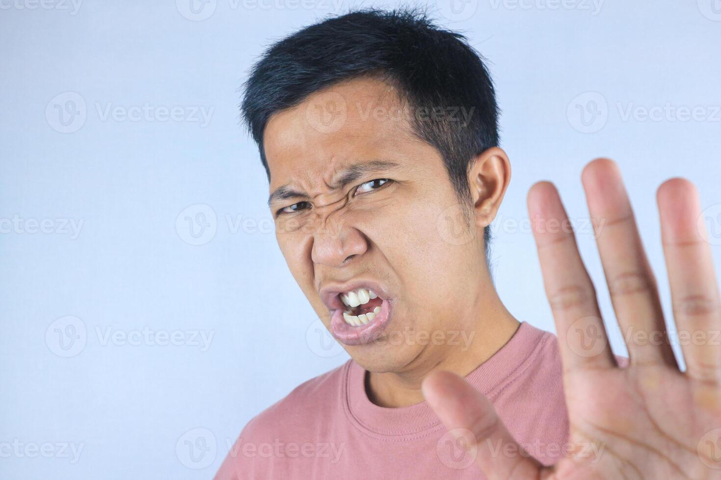 funny face expression young asian man looking at camera while gesturing refuse hand photo