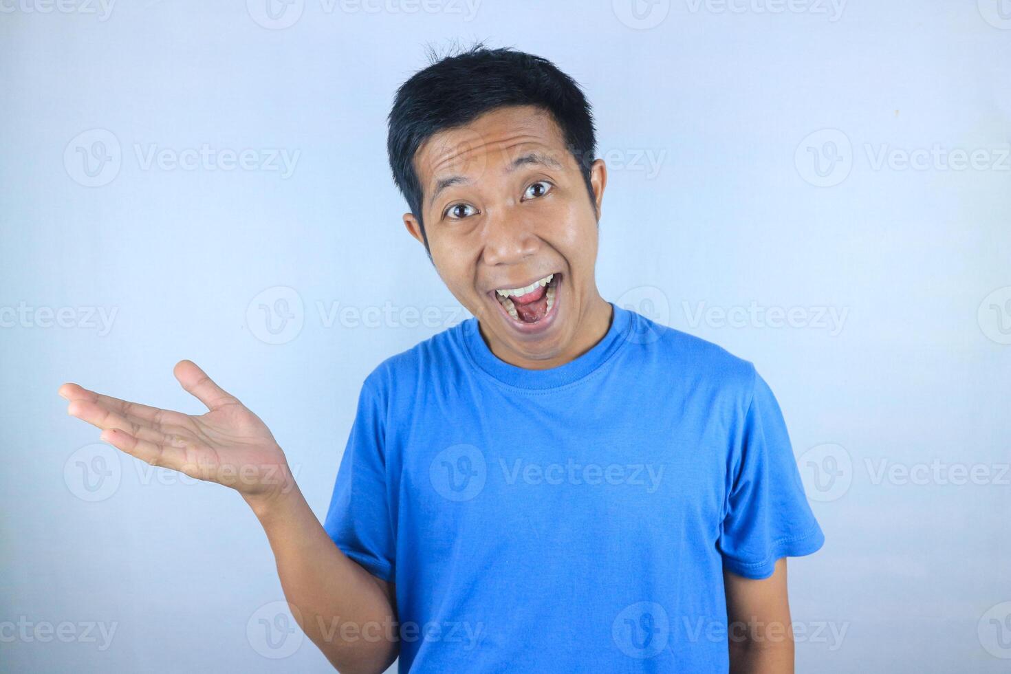 funny face expression of smiling young asian man showing right side with his hand promoting product photo