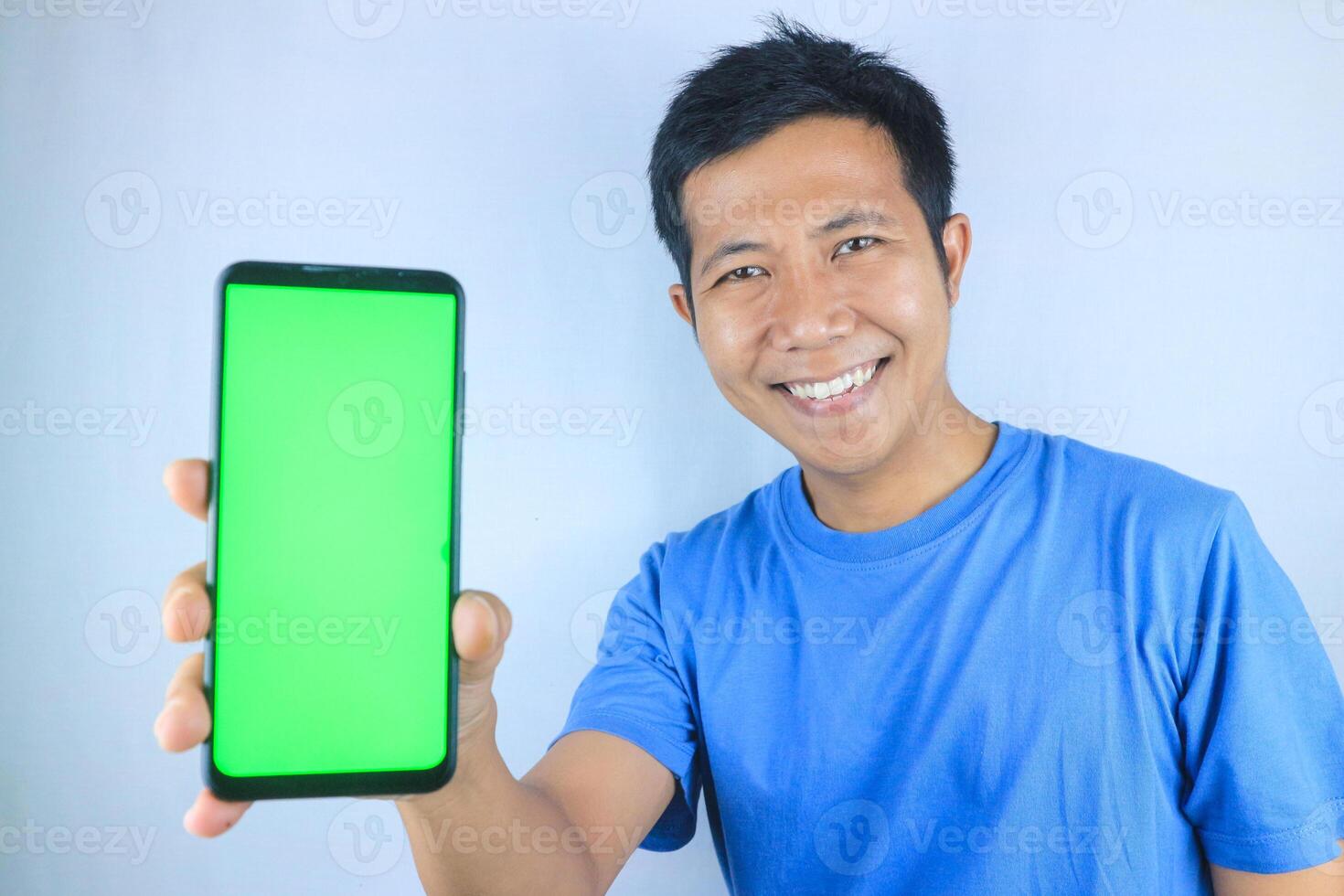 Young asian man smiling while showing an empty phone screen on white background, looking at camera photo