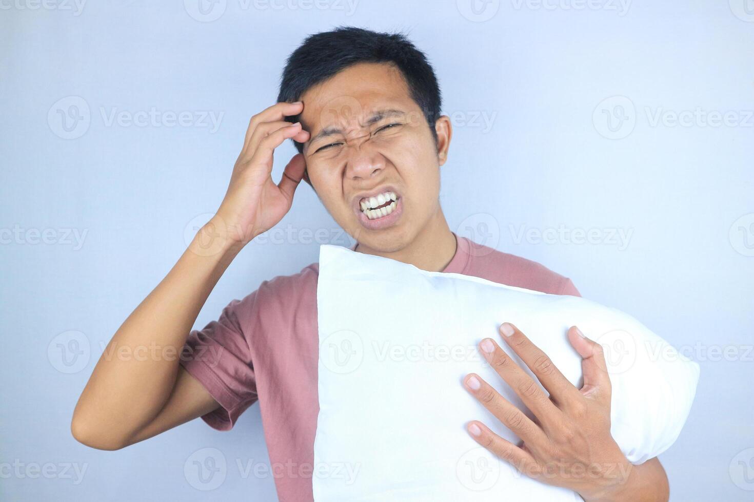 asian man expression feeling headache, migraine while holding pillow isolated on white background photo