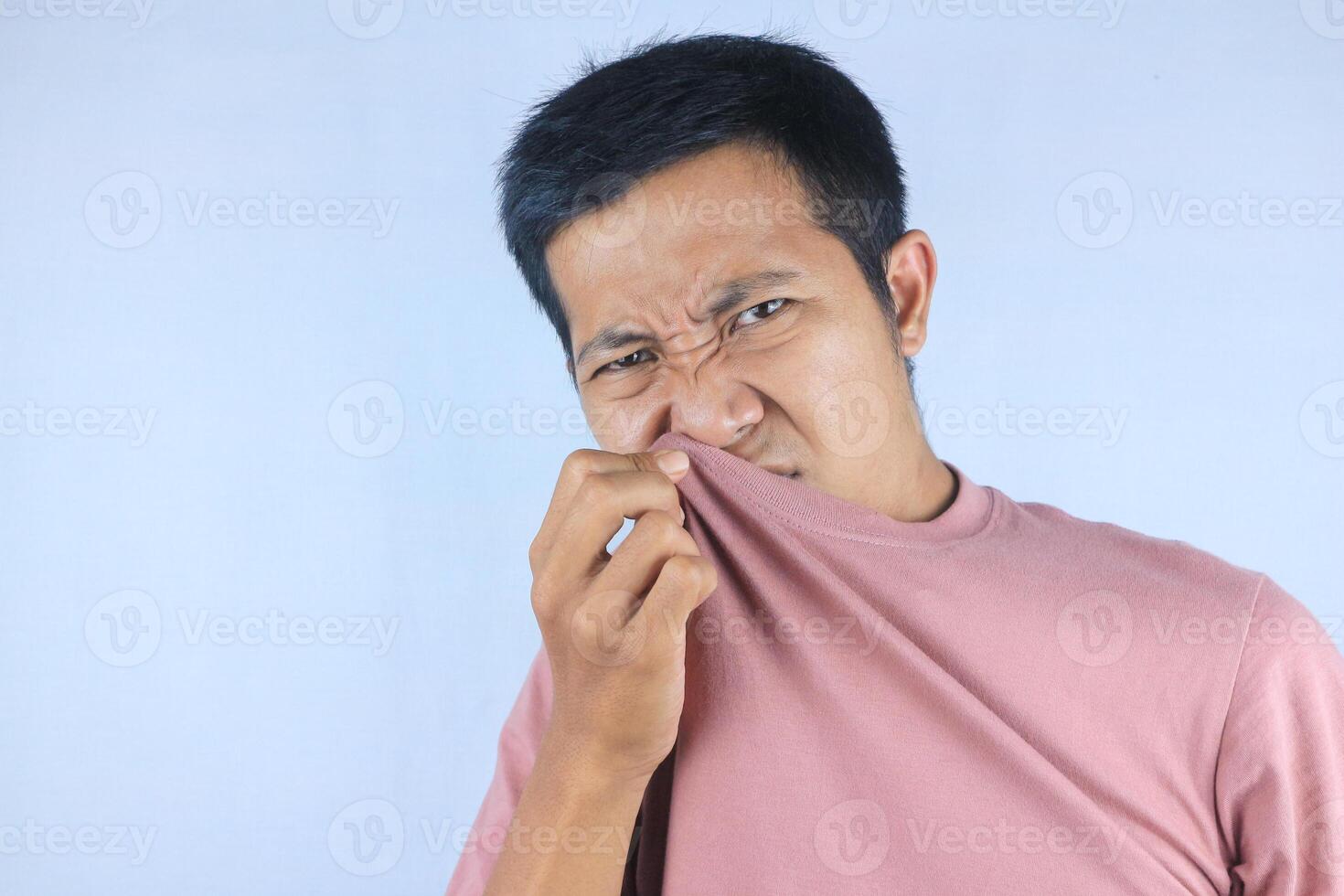 Asian man check his own smell, sniffing his wet armpit or sweating, isolated on white background photo