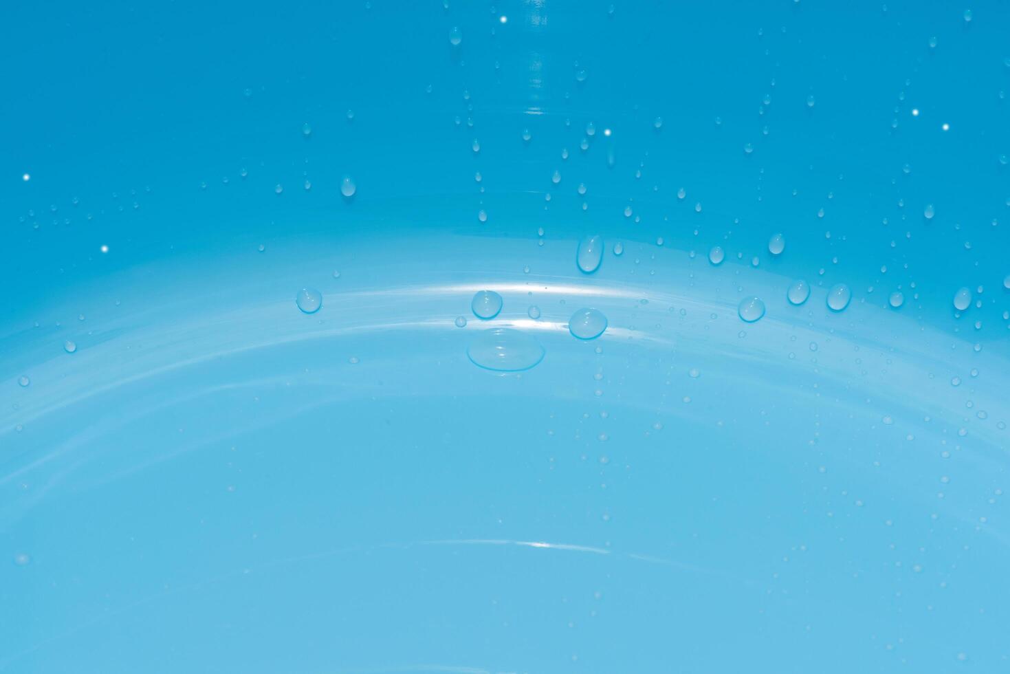 Blue water with ripples on the surface. Defocus blurred transparent blue colored clear calm water surface texture with splashes and bubbles. Water waves with shining pattern texture background. photo