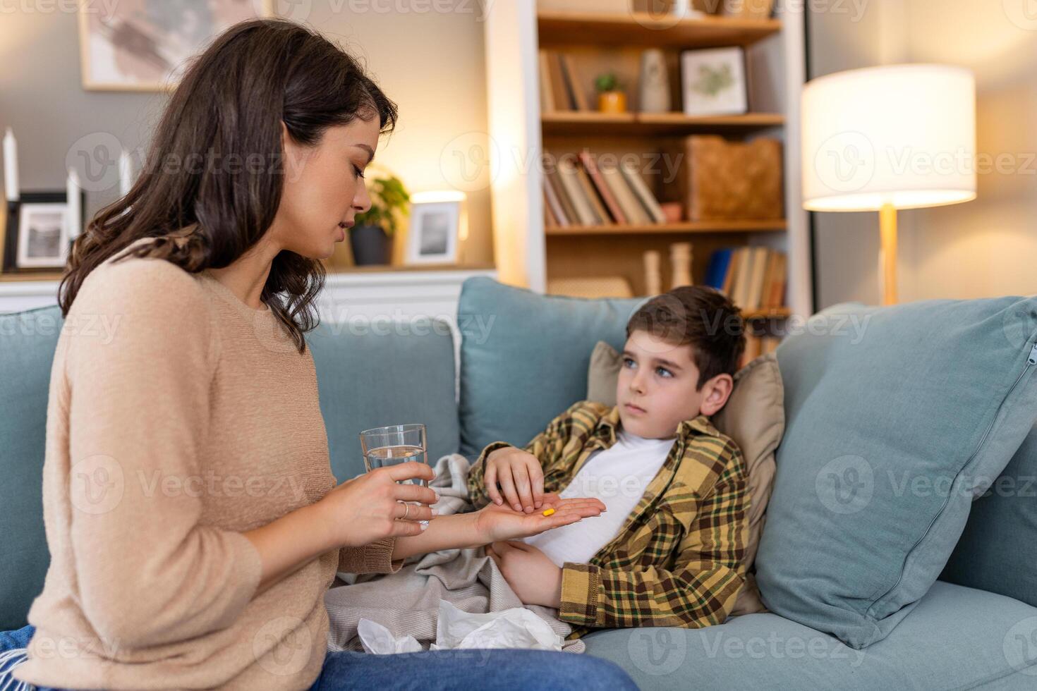 A child with a cold, swallowing medicine to combat illness. His mother tends to him, ensuring his comfort and care as he rests in bed at home, aiming for a swift recovery from the virus. photo