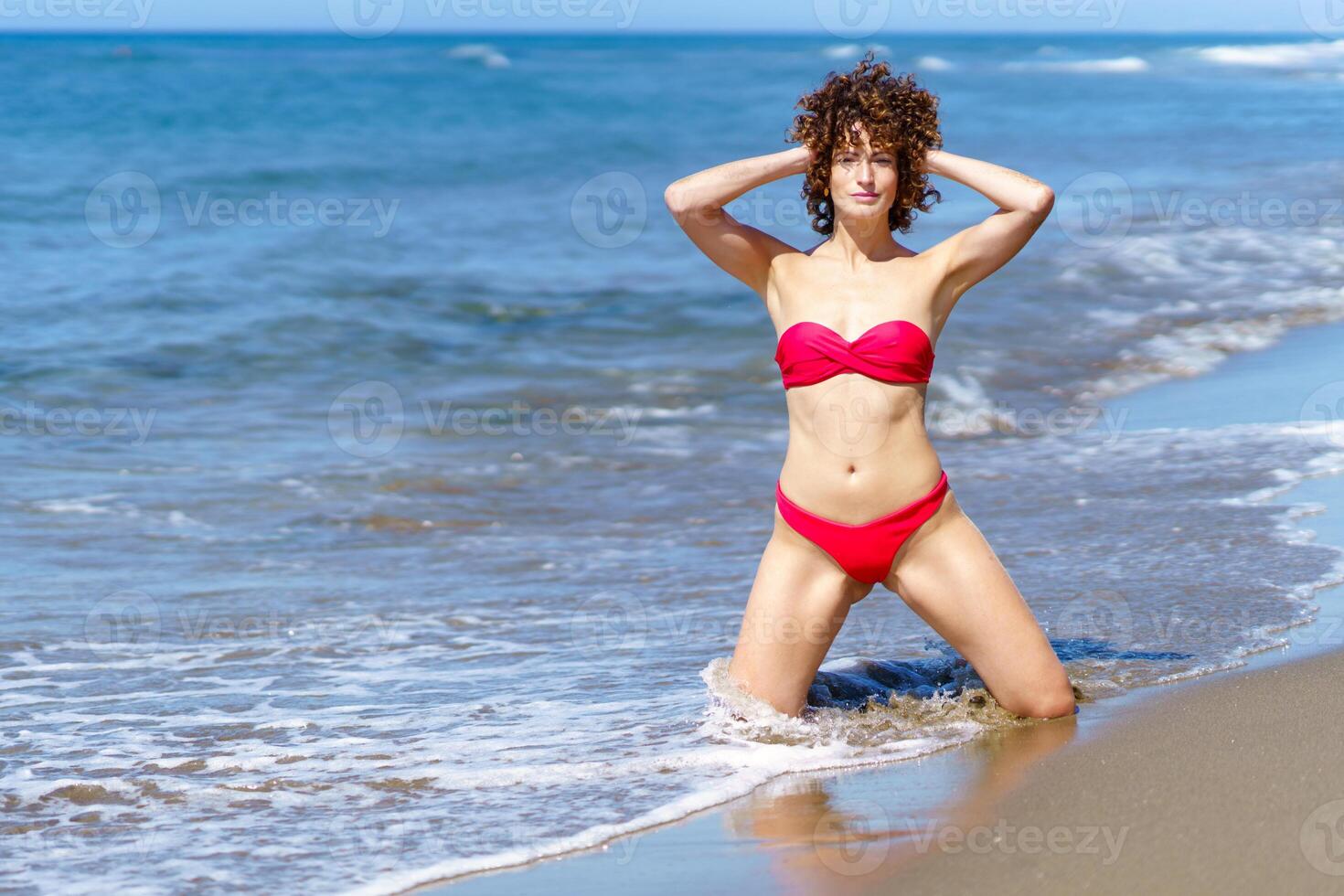 Slim woman in bikini in shallow sea water photo