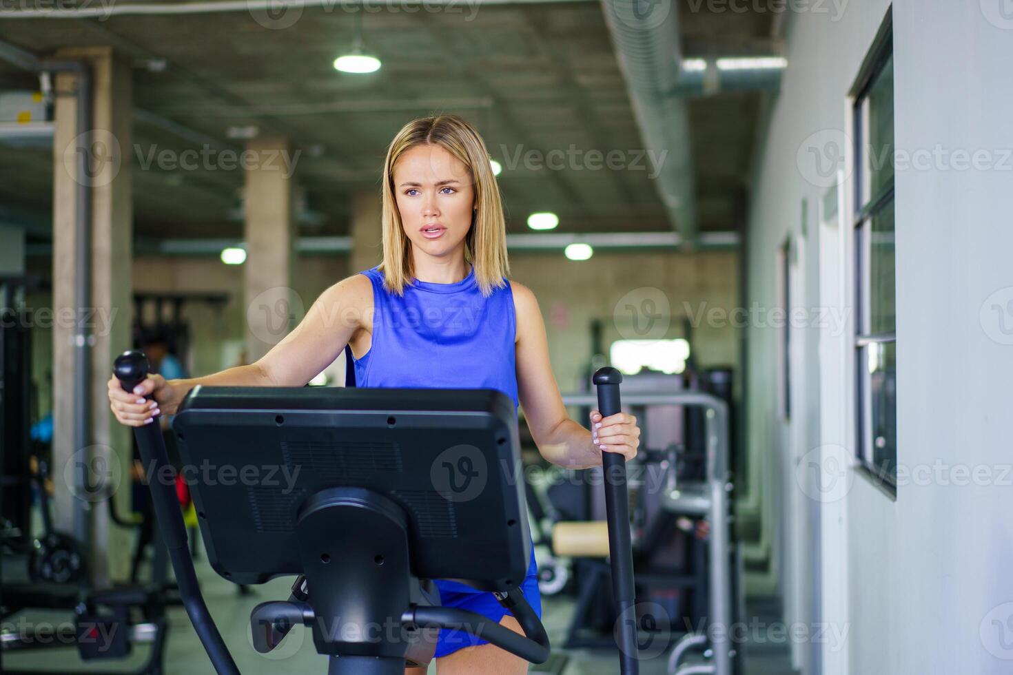Woman exercising on elliptical machine in the gym photo