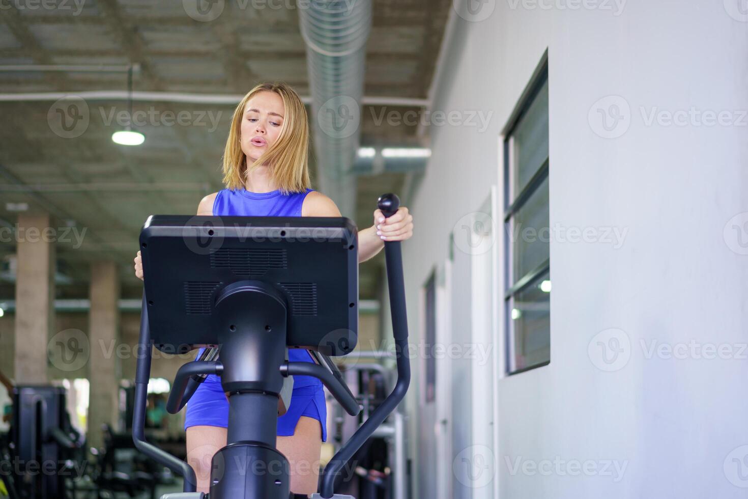 Woman exercising using elliptical machine in the gym photo