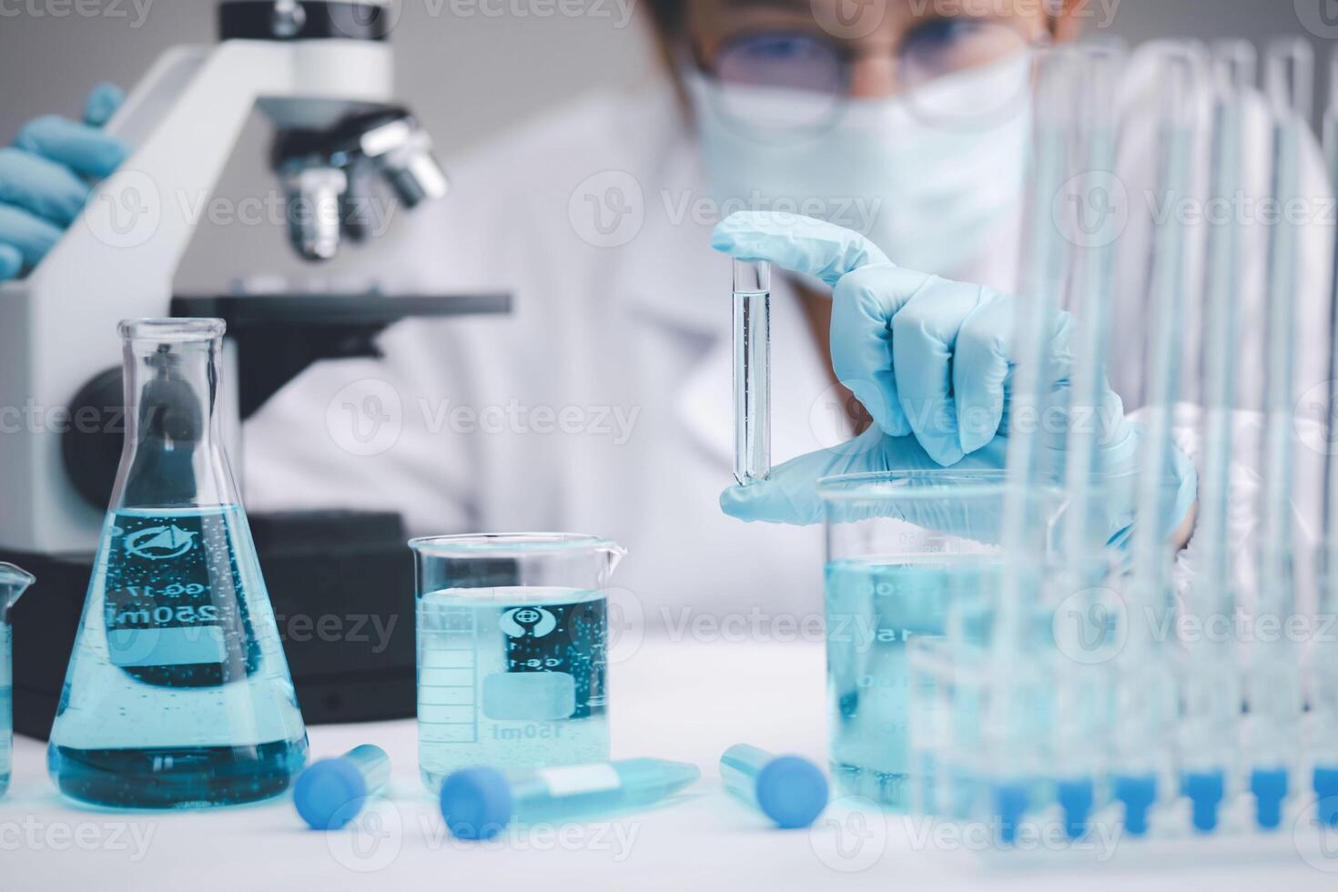 biochemical research scientist working with a microscope for the virus,Doctor man write a history of the experimental results in a , laboratory glassware containing chemical liquid for design. photo