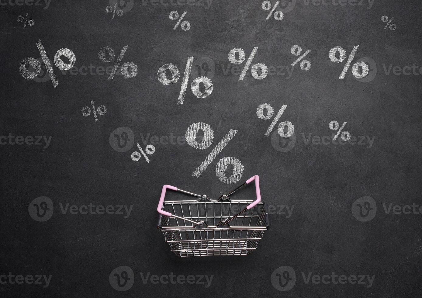 Miniature shopping metal cart on a background of a black chalk board with drawn percentages, discount start concept photo