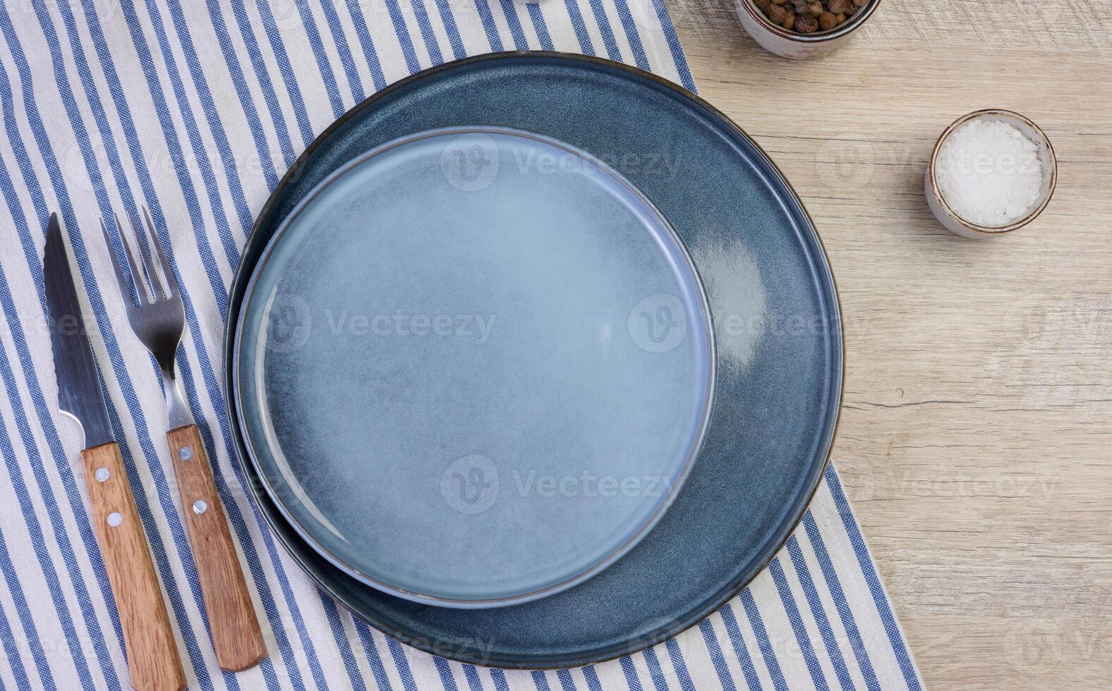 Empty round ceramic plate on the table with spices, top view photo