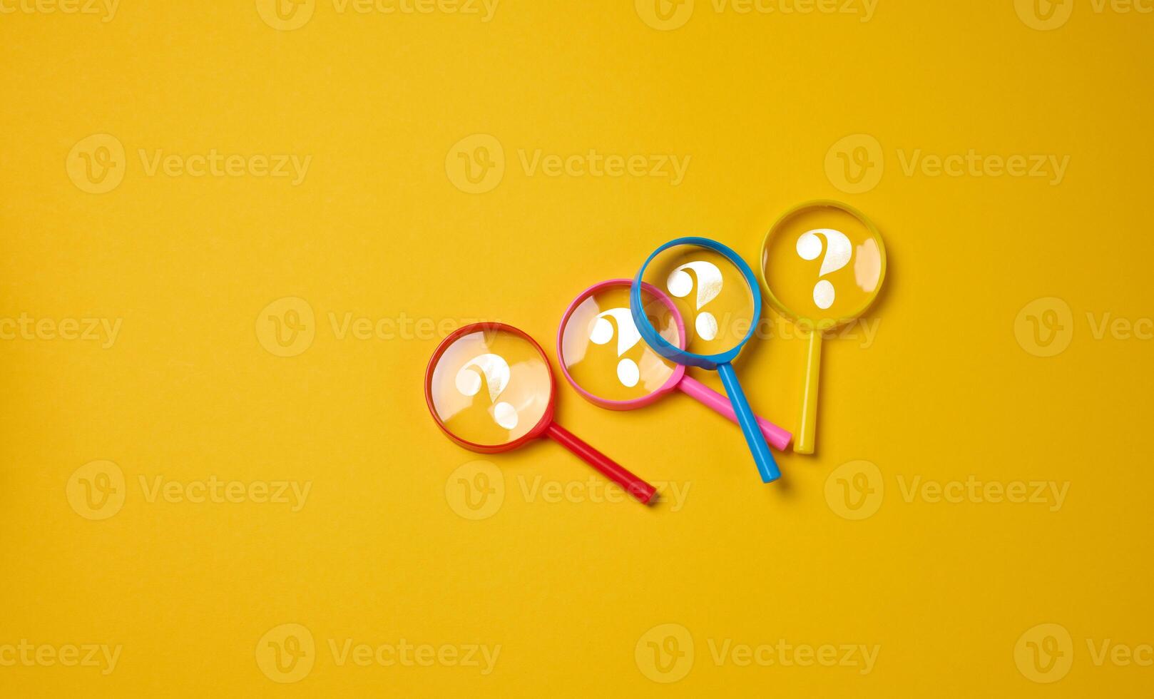 Plastic multi-colored magnifying glasses with a question mark on a yellow background photo