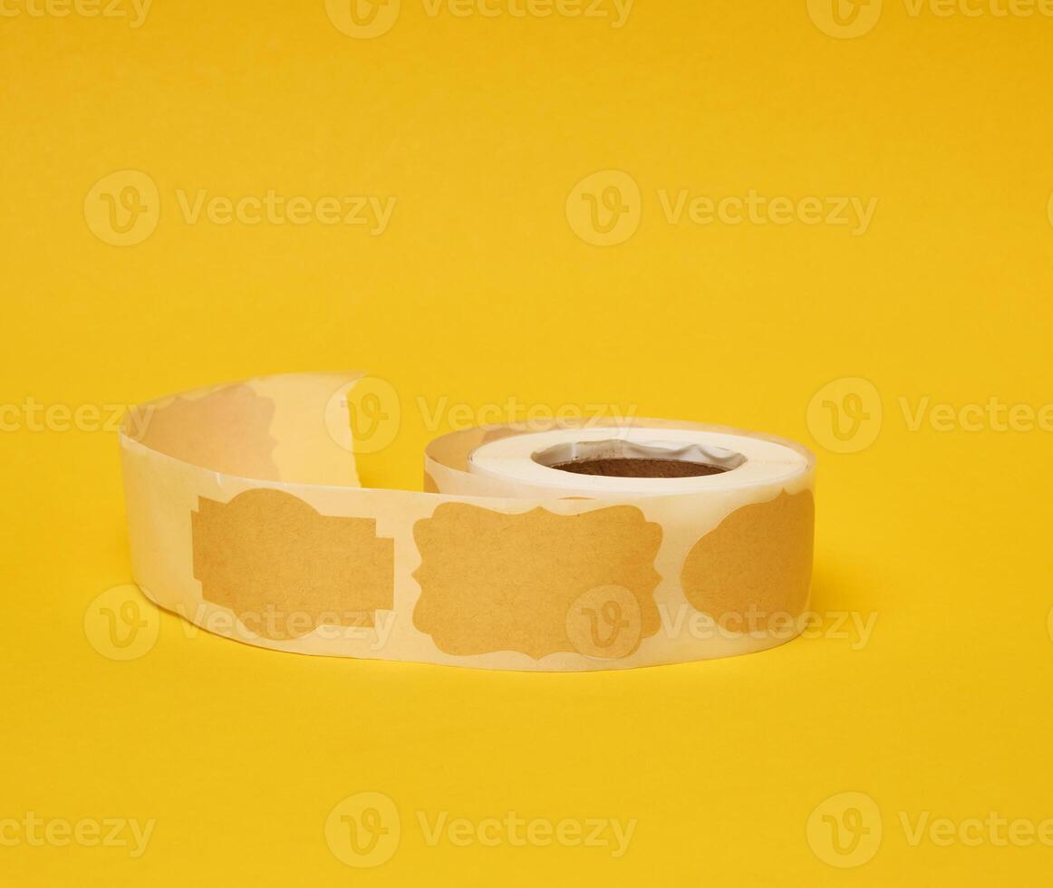 Sticky empty brown paper labels on tape, yellow background photo