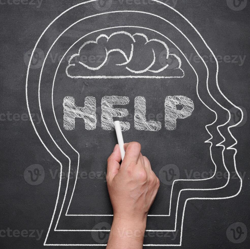 The silhouette of a human head is drawn on a black chalk board, the inscription help. Mental health concept photo