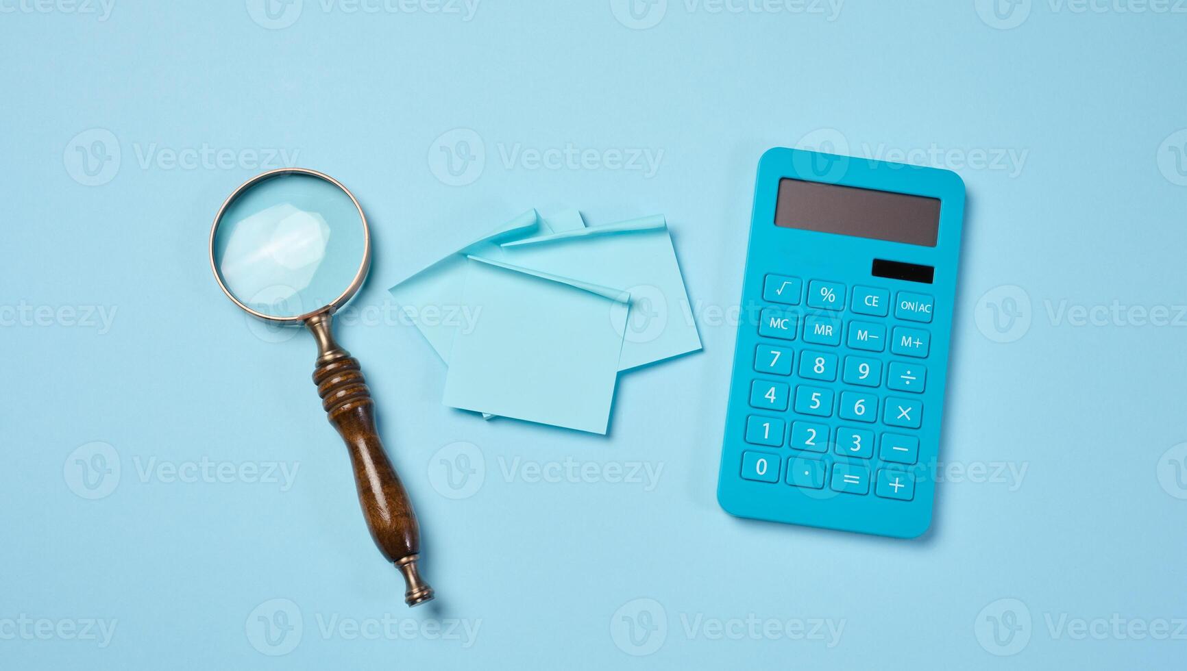 Magnifier and calculator on a blue background, budget calculation. photo