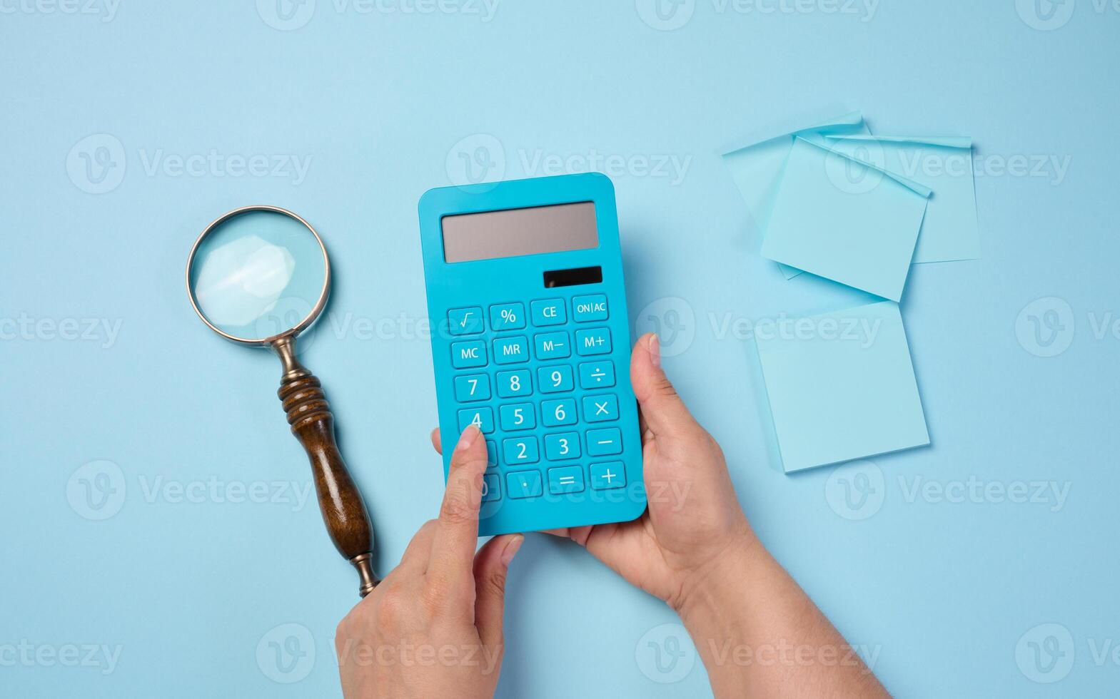Magnifier and calculator on a blue background, budget calculation. photo