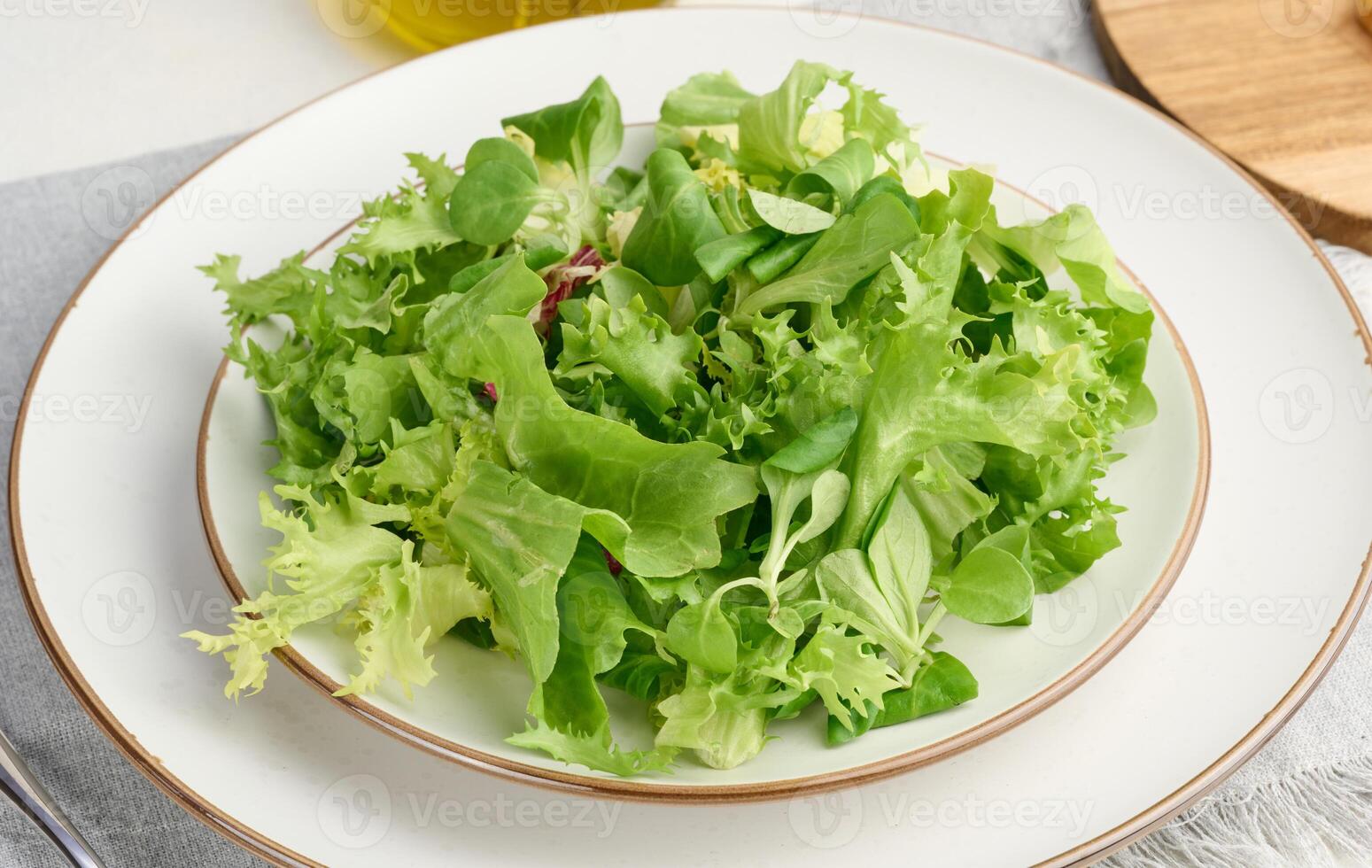 Fresh green lettuce leaves in a white plate on the table, healthy food photo